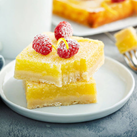 lemon bars topped with raspberries and sprinkled with powdered sugar