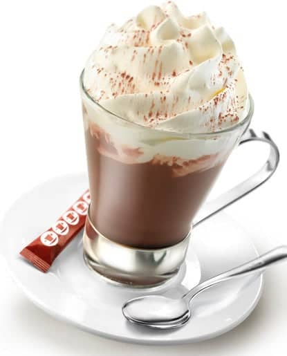 Glass cup filled with mocha and whipped cream, on a saucer with sugar and spoon
