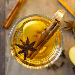 anise, apple slice and cinnamon stick in beverage in glass mug