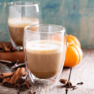 pumpkin spice latte in glass tumbler next to cinnamon sticks